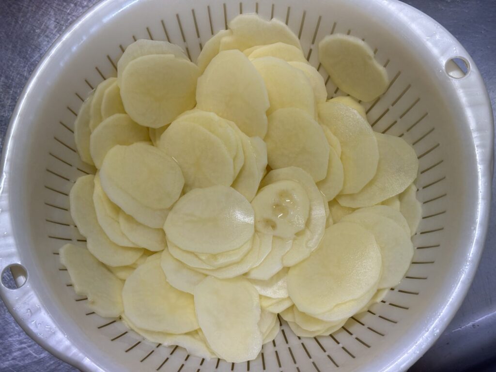 ザルに上げた、スライスしたジャガイモ100枚くらい。
