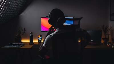 コンピューターの前に座っているヘッドホンを装着している人