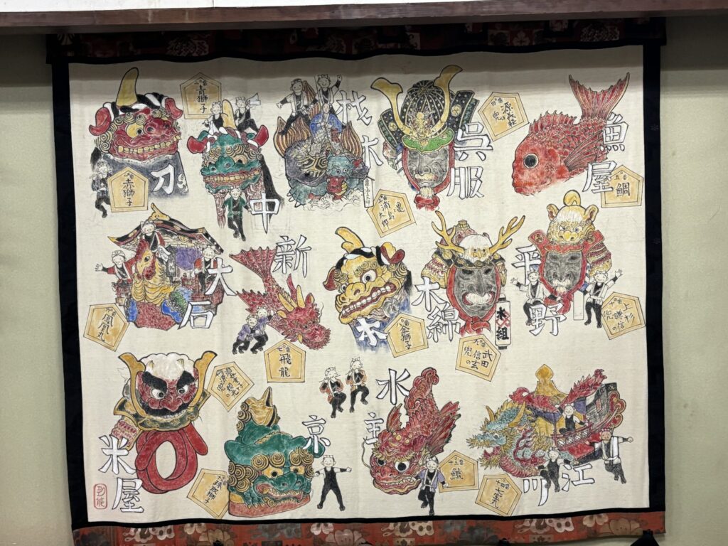 夕食会場で「唐津くんち」の１４町の曳山の絵を大きな布に書いてあるものの画像