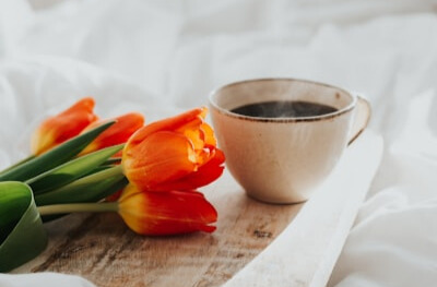 薔薇の花とコーヒーカップに入って湯気の出ているコーヒー：朝の雰囲気が出ている