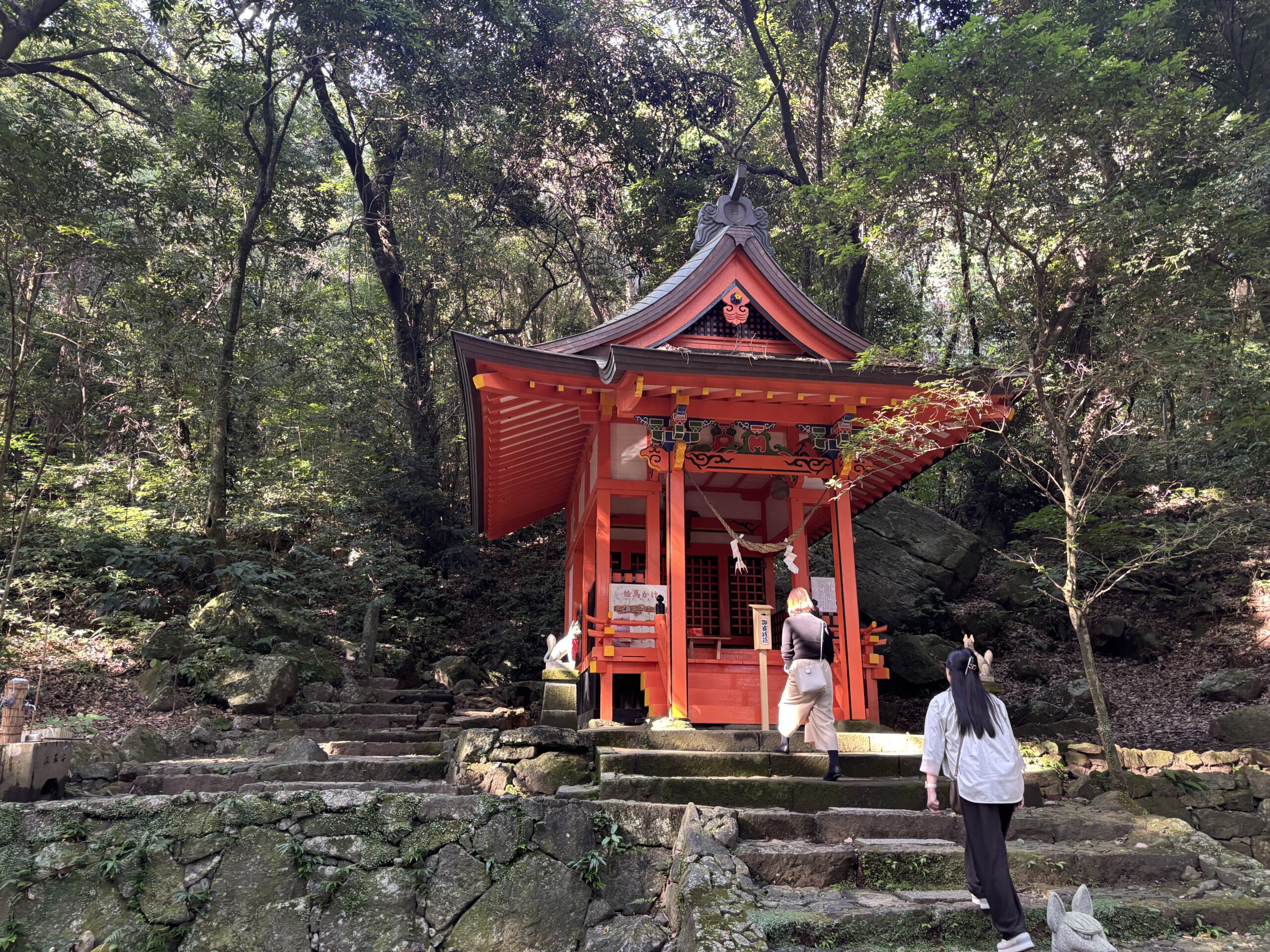 鹿児島神宮の裏側にある「稲荷神社」の写真 二人の女性の背中がいっしょに写っている